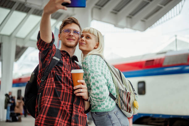 istock Couple taking selfie with a phone and drinking coffee on a train station 2043670602