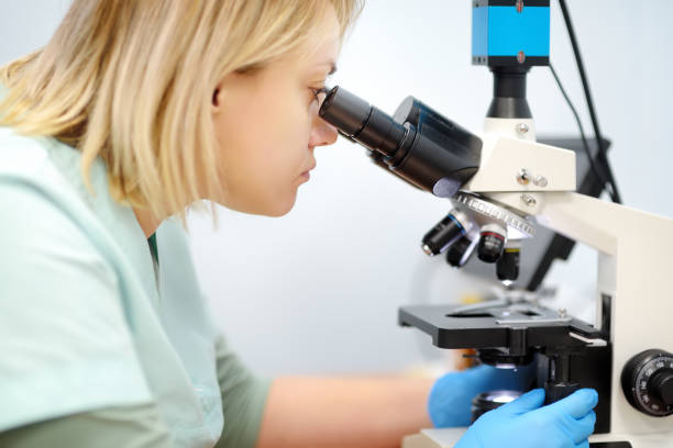 istock Young female scientist chemist or biologist analyzing new substance or virus in microscope. Woman in a laboratory for medical, forensic or microbiological research. Lab for pharmaceutical development 2043682014