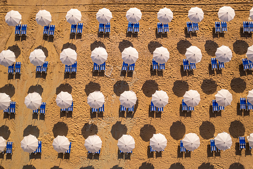 Aerial view of sandy beach with rows of parasols at sunrise, Mediterranean Sea, Italy