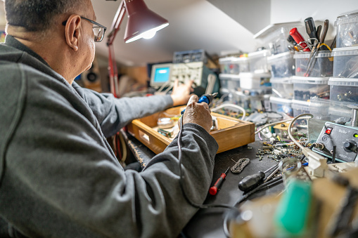 Senior man using a soldering iron medtronic at home