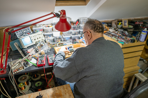 Senior man repairing electrical equipment at home