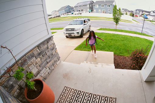 Security camera showing the front door of a home with children coming and going.