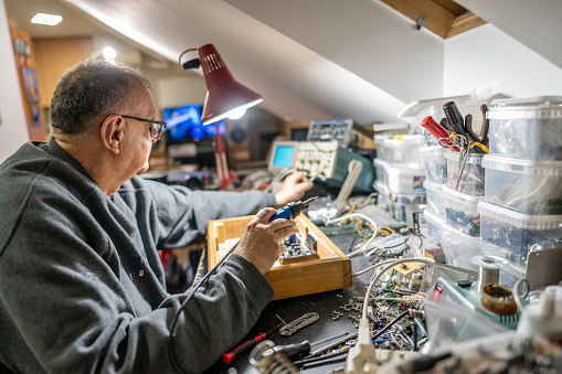 Senior man using a soldering iron medtronic at home