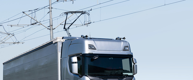 Electric semi truck with pantograph takes energy from wires above the highway.