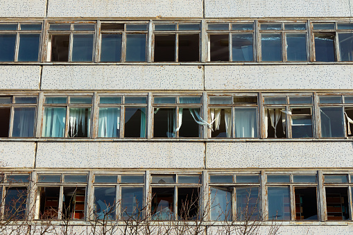 Facade of an abandoned multi-story building with broken glass in the windows