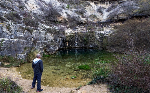 DCIM\\100MEDIA\\DJI_0533.JPGA man contemplates the blue water well in a rural area, marveling at its depth and the tranquility it emanates, connecting with nature.\nBlue Well of Covanera, Burgos, Spain