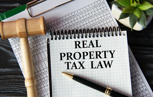 REAL PROPERTY TAX LAW - words on a white sheet on the background of a judge's gavel, a cactus and a pen
