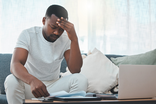 Stress, debt or black man with documents or laptop in home for budget, planning savings or anxiety. Financial crisis, bills or frustrated African person checking invoice, payment or balance paperwork