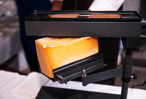 Golden raclette cheese melting on an electric griller device