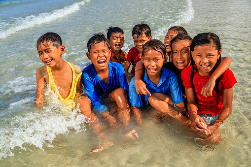 Group of happy Cambodian children playing in the sea, Cambodia
