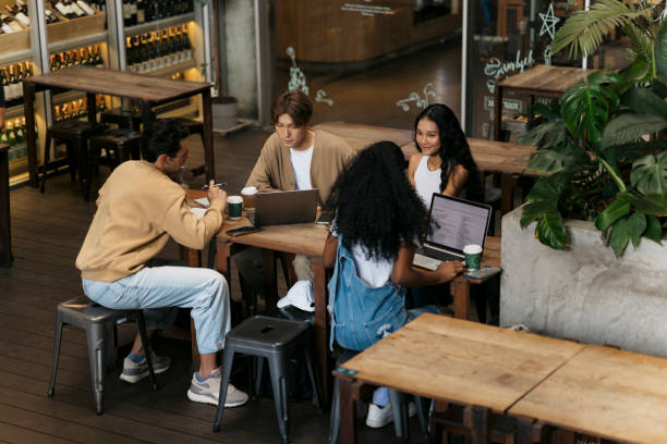 Two young friends sitting at coffee shop looking at a laptop and discussing. Man and woman friends working together on a laptop computers sitting at cafe.