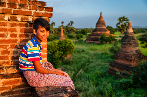 Young Burmese boy with thanaka face paint looking at an ancient temples of Bagan, Myanmar (Burma)