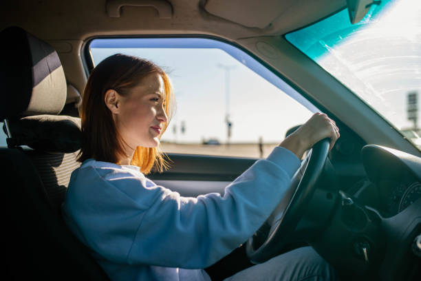 istock young woman driver driving a car on a sunny day. 2044001895