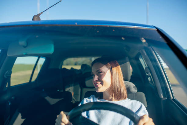 istock young woman driver driving a car on a sunny day. 2044001900