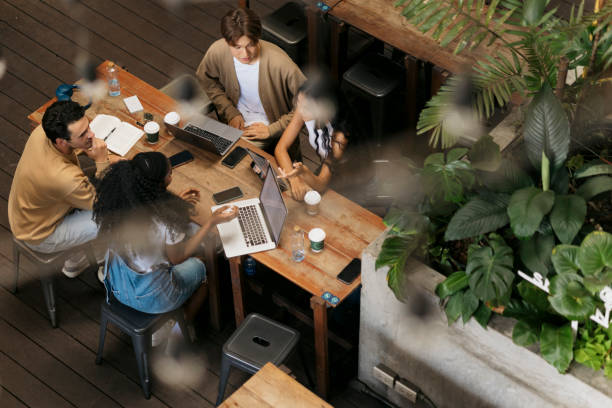 istock Group of college students sitting around cafe table discussing assignment 2044004476