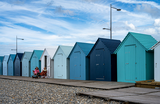 Blue beach huts, in water front on the beach in Dieppe, Normandy, France.\nAugust 12, 2023.