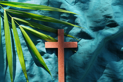 Palm leaves with wooden crucifix cross flat lay composition. Palm sunday celebration background.