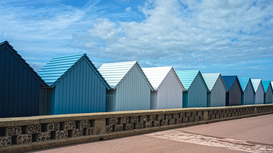 Blue beach huts, in water front on the beach in Dieppe, Normandy, France.