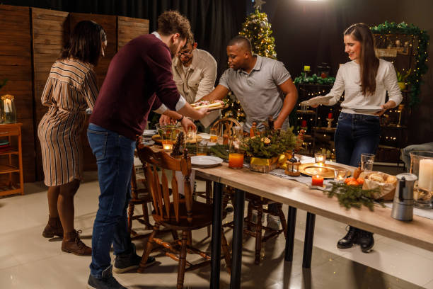 istock Group of friends working as a team and setting up the table for a Christmas dinner party 2044063219