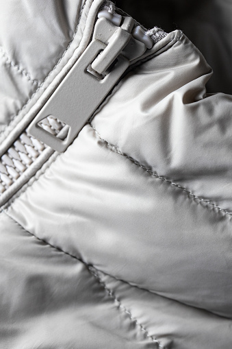 Padded coat in grey color with zipper. Close up of detail and fabric texture