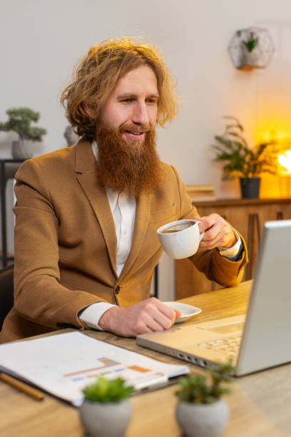 istock Business man freelancer at home office table drinking morning coffee and working on laptop computer 2044072520