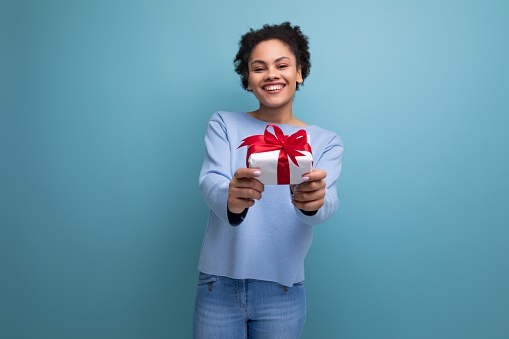 positive young brunette lady with afro curls gives a gift.
