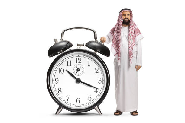 Saudi arab man in ethnic clothes with a big alarm clock isolated on white background