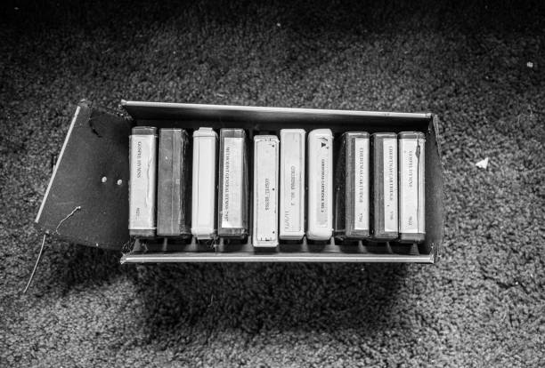 A broken box of labeled carillon cartridges of gospel and Christmas music sits on the floor of an abandoned church.