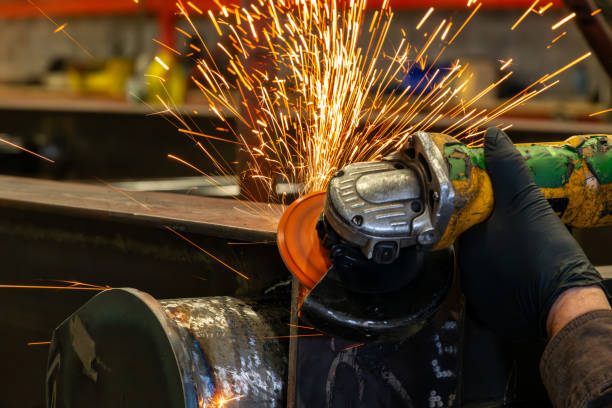 Worker grinding steel structure using an electric grinder in the factory