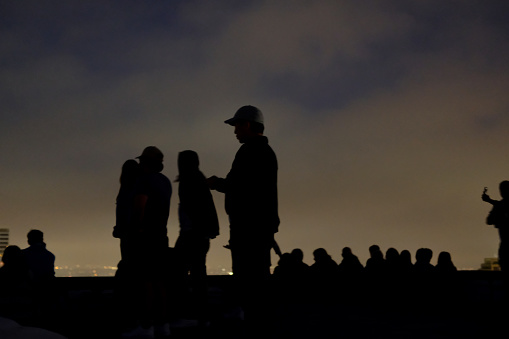 Mixed group of people hanging out on rooftop deck at a party or get together to enjoy an evening under the clouds.