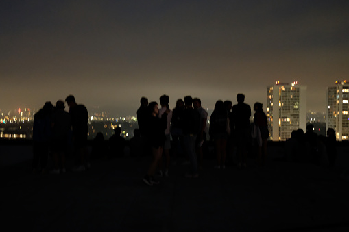 Mixed group of people hanging out on rooftop deck at a party or get together to enjoy an evening under the clouds.