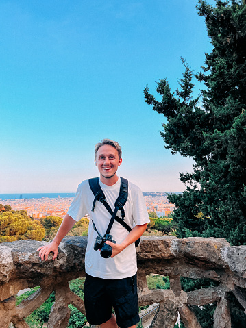 Handsome, Smiling Young Man, Solo Traveler with a Professional Camera Visiting Park Güell in Barcelona, Spain