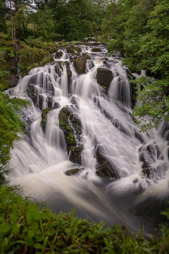 Beautiful cascading waterfall through a lush green landscape - Rhaeadr Ewynnol / Swallow Falls in Betws y Coed, North Wales