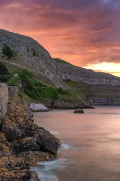 Photo of Vibrant colorful sunset over a dramatic rugged coastline surrounded by cliffs. North Wales