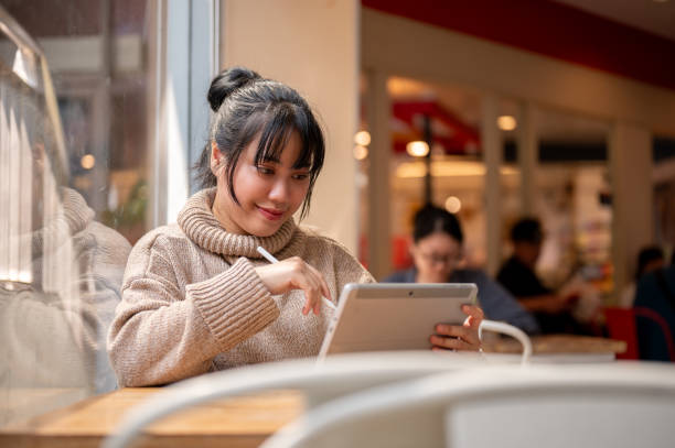 istock An attractive, happy Asian female is working remotely at a cafe co-working space, using her tablet. 2044458720