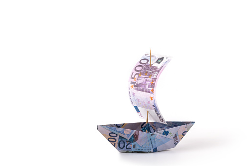 A paper boat made from euro banknotes of various denominations and a sail made from a 500 euro bill