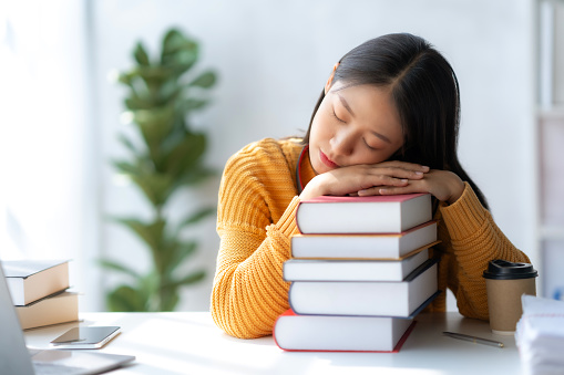 Young asian woman sleeping on table tired after read book.