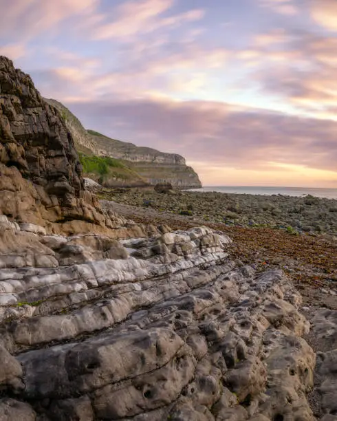 Photo of Sunrise over a rugged rocky coastline with colorful limestone layers - North Wales