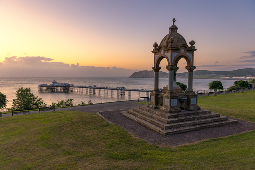 Sunrise glow over the Queen Victoria Memorial and Fountain and Llandudno Pier in North Wales, United Kingdom