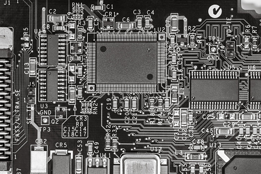 closeup of circuit board with resistors, condensers, microchips and electronic components. b/w.