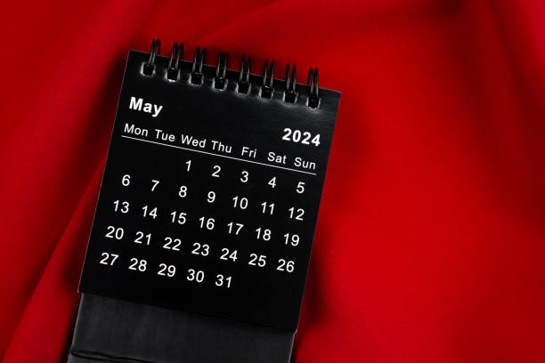 istock May 2024 Black spiral desktop calendar on red textile. 2044607827