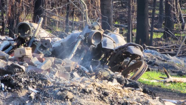 Burnt Motorcycle Remains On Smoky Ashes And Debris In The Forest. Wildfire Aftermath In Alberta, Canada. closeup shot