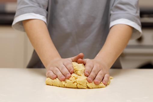 boy's hands are pressing the cookie dough to the table