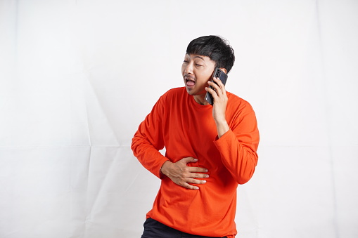 male laughing holding his hands on stomach can`t stopping laughing after hearing funny anecdote on call