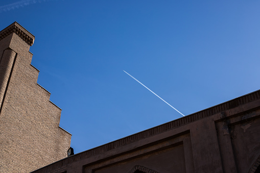 airplane trail on blue sky, triangle of buildings, Uzbekistan