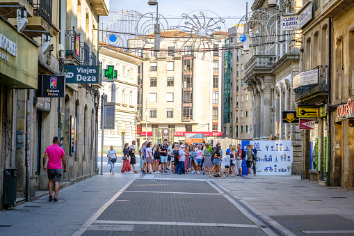 Pontevedra, Spain - August 6, 2022: Many tourists listen to the explanations of their guide in one of the streets of the city.