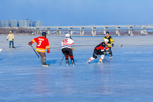 Harbin, Heilongjiang, China - December 6th 2018 - Photo of people playing ice hockey on outdoor rink in winter