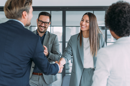 Business people shaking hands in the office. Business persons handshaking during a meeting in modern office.