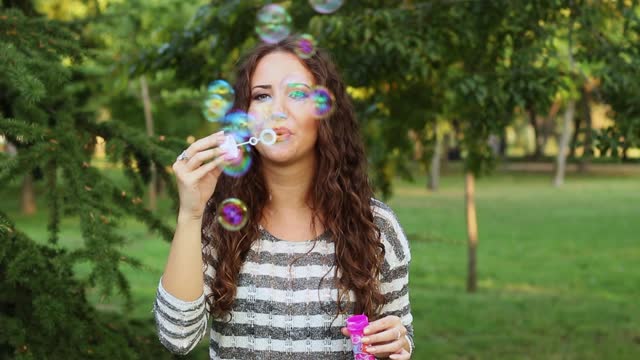 Young Woman Blowing Bubbles In The Park
