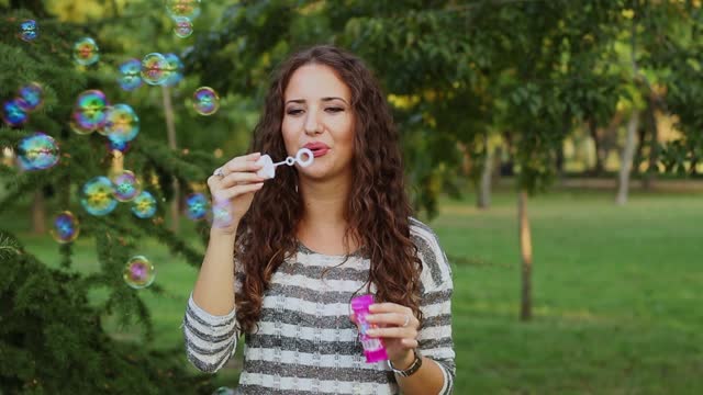 Young Woman Blowing Bubbles In The Park